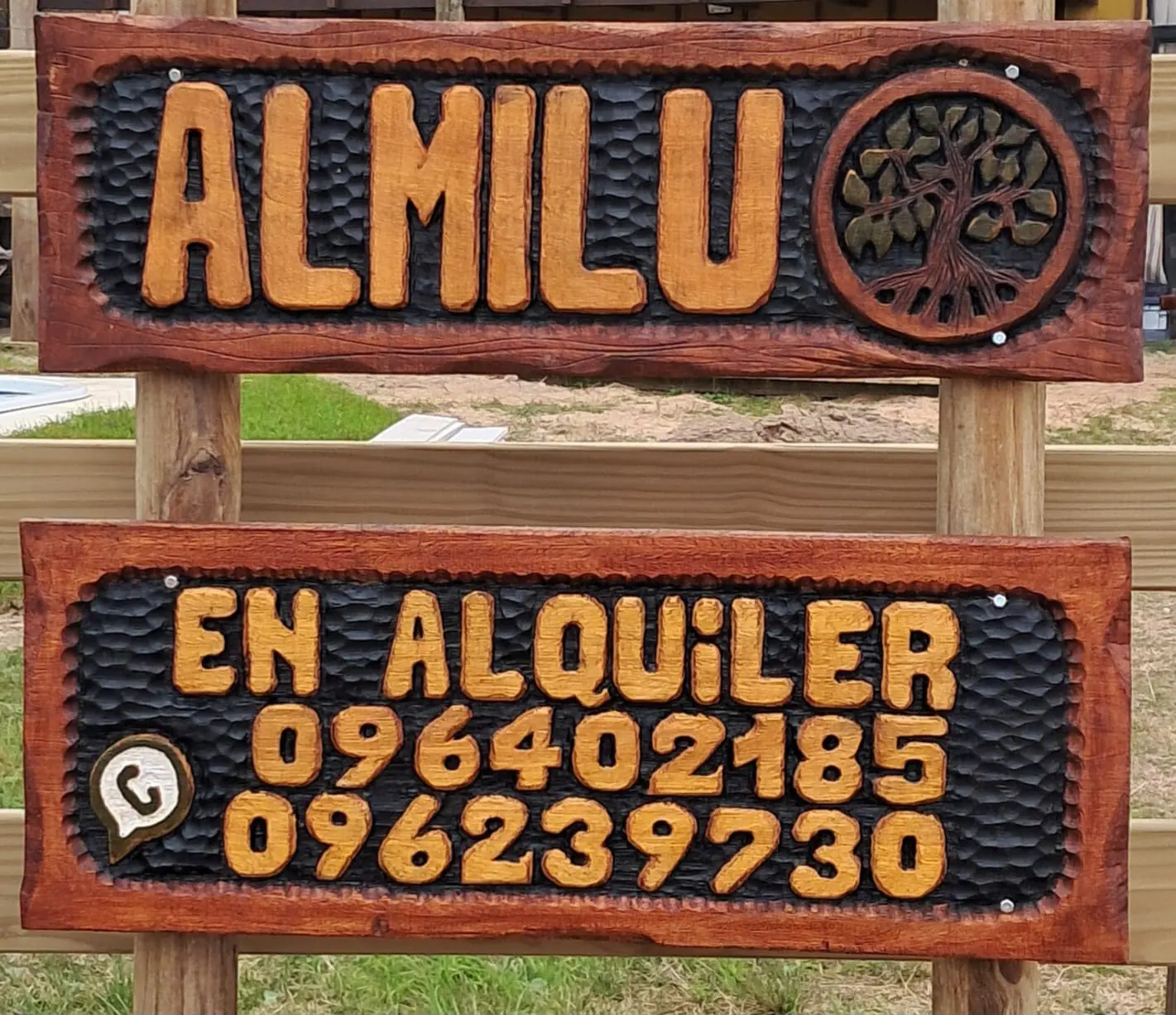 Cartel de madera tallada con el nombre ALMILU y un árbol de la vida dentro de un círculo